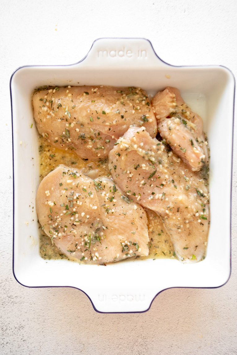 Chicken being marinated in honey rosemary sauce.