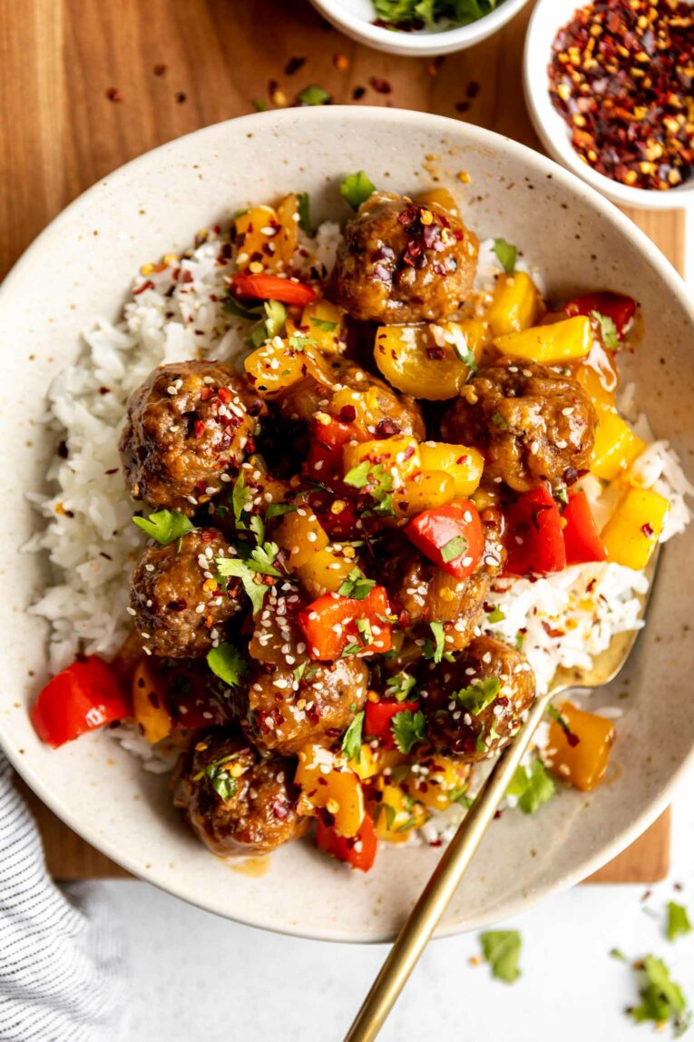Sweet and sour meatballs with veggies and rice in a large bowl.