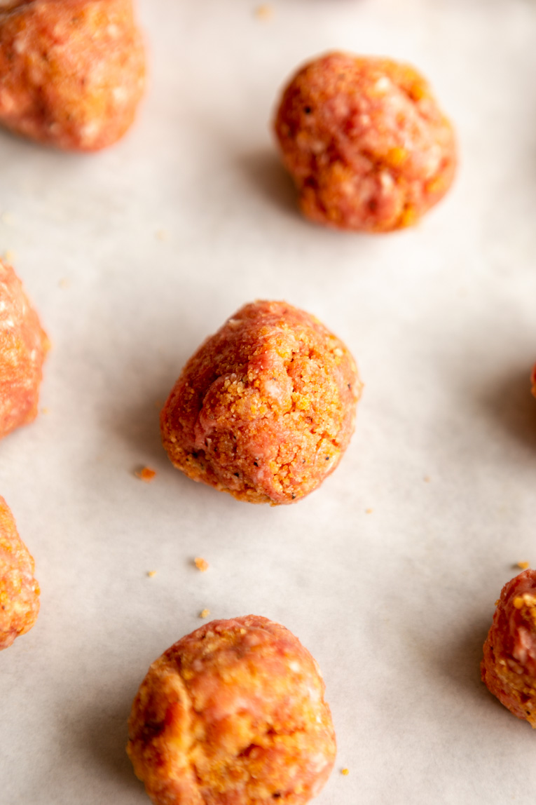 Ground beef meatballs on a baking sheet.