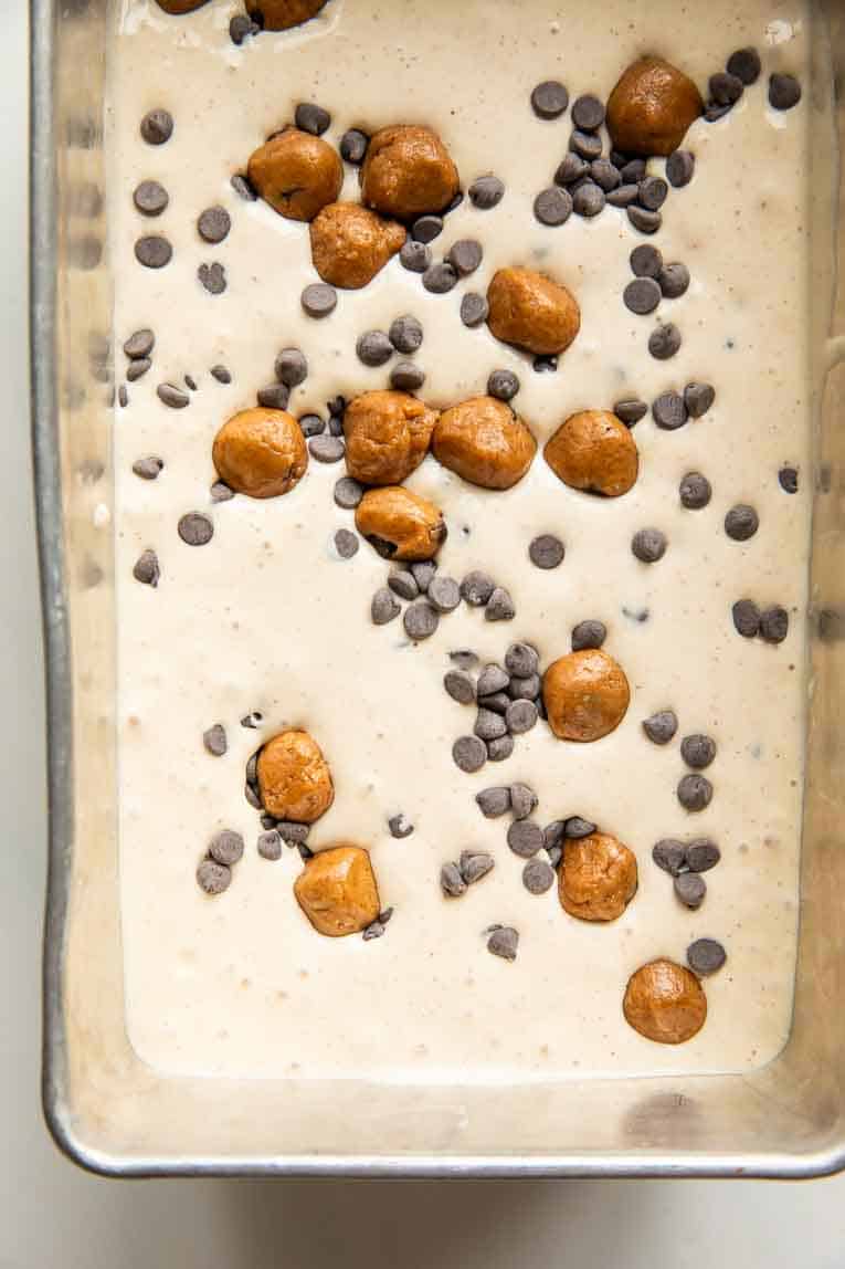 Cookie Dough Ice Cream batter in a loaf pan with chocolate chips and protein cookie dough bites.