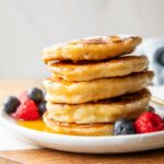 Cottage Cheese Pancakes recipe stacked on a plate with syrup.