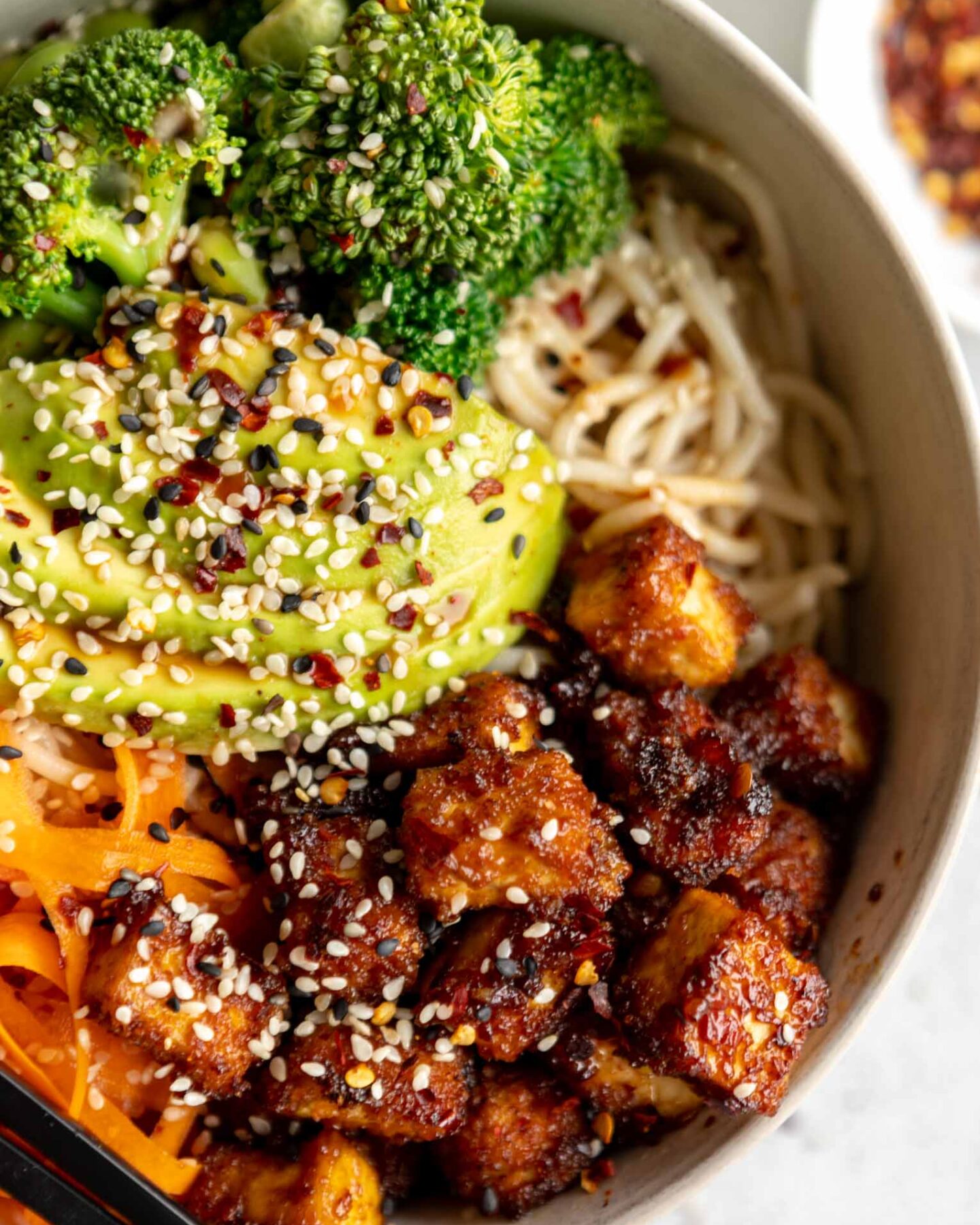 Asian fried tofu with avocado, veggies, and noodles.