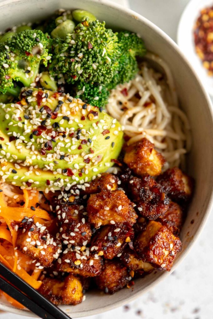 Asian fried tofu with avocado, veggies, and noodles.