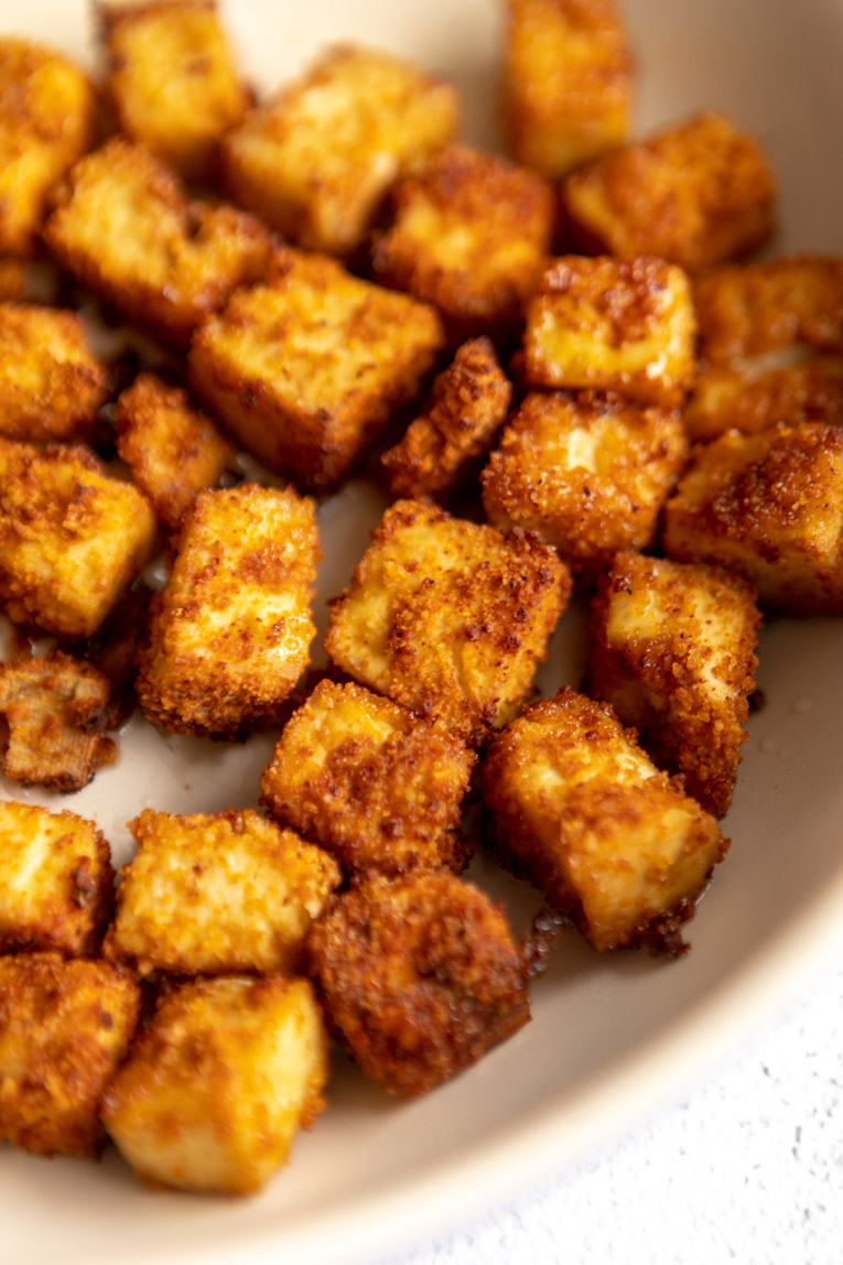 Fried tofu cooking in a non-stick skillet.