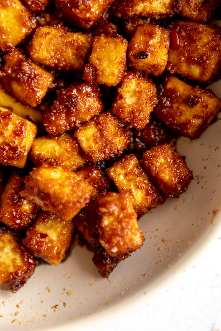 Fried tofu with sweet and spicy sauce cooking in a pan.