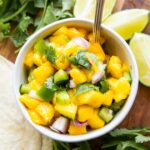Styled Mango Salsa Recipe in a small bowl with a spoon.