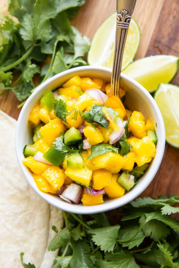 Styled Mango Salsa Recipe in a small bowl with a spoon.