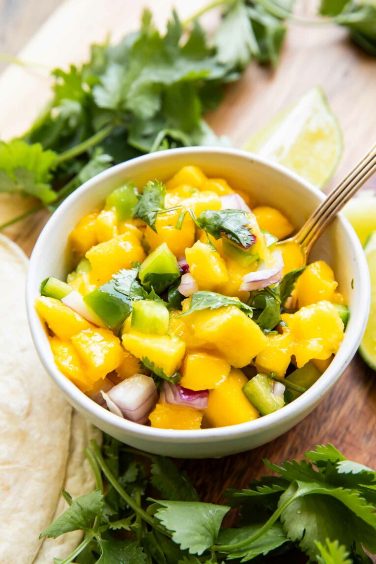 Angled photo of styled Mango Salsa Recipe with a spoon.