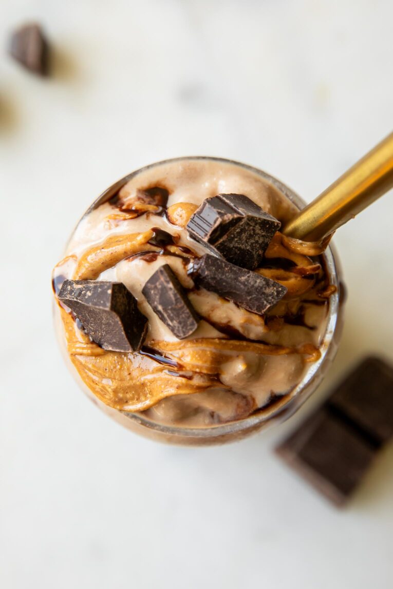 Top shot of Ninja Creami Protein Milkshake recipe in a glass with chocolate syrup, peanut butter, and chocolate chunks.