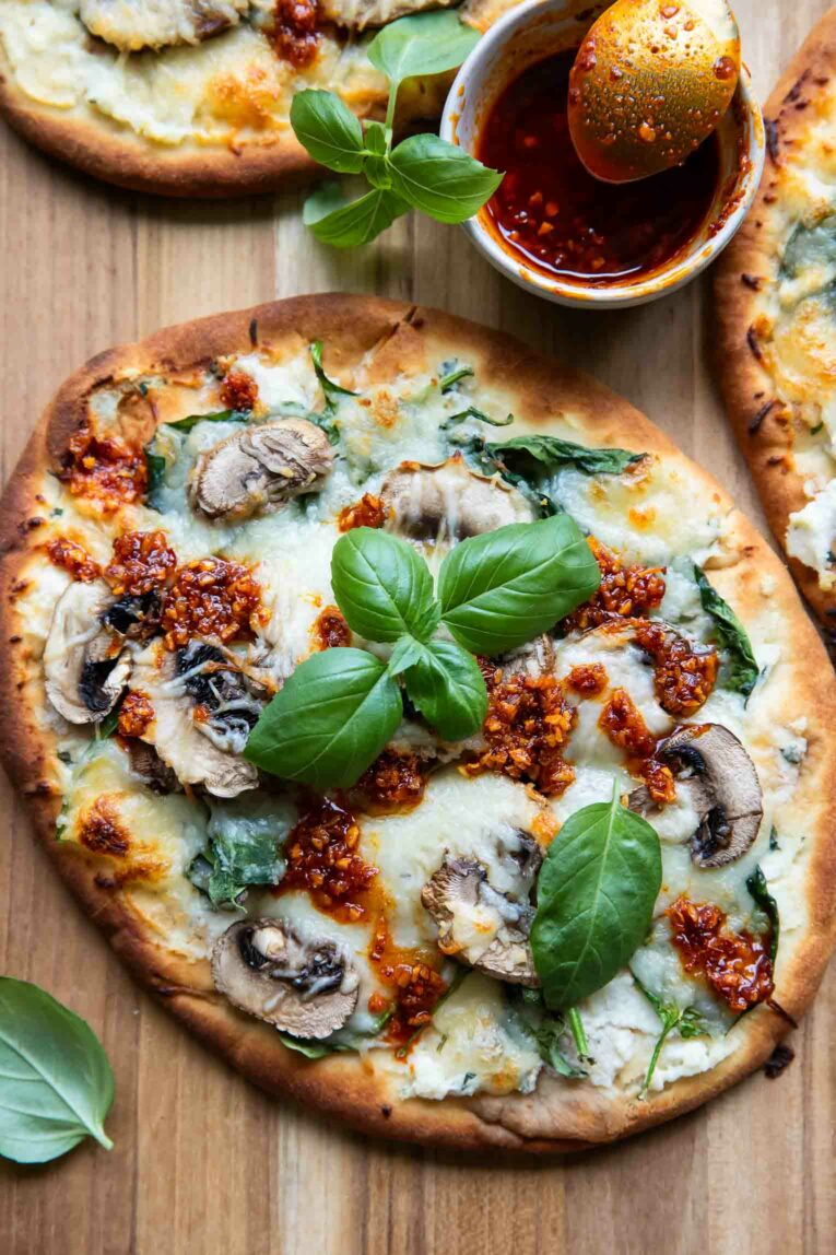 Spinach & Mushroom Naan Pizzas with chili crunch and basil.