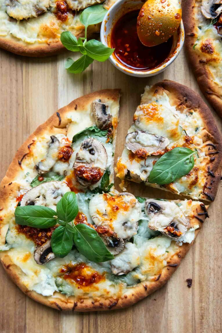 Spinach & Mushroom Naan Pizza with slice taken out.