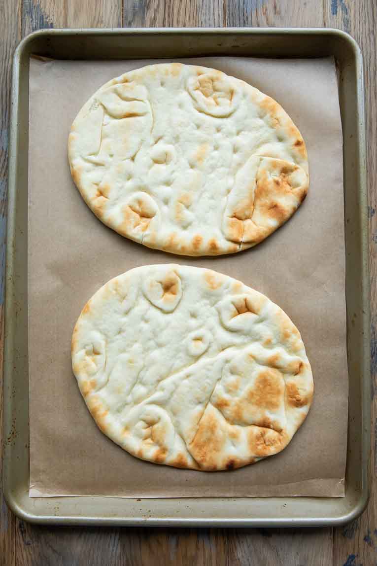 Naan bread on a sheet pan.