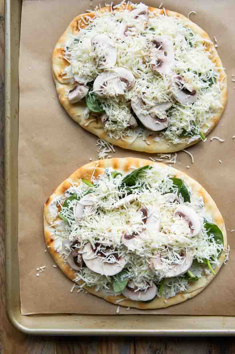 Spinach & Mushroom Naan Pizzas on a sheet pan before baking.