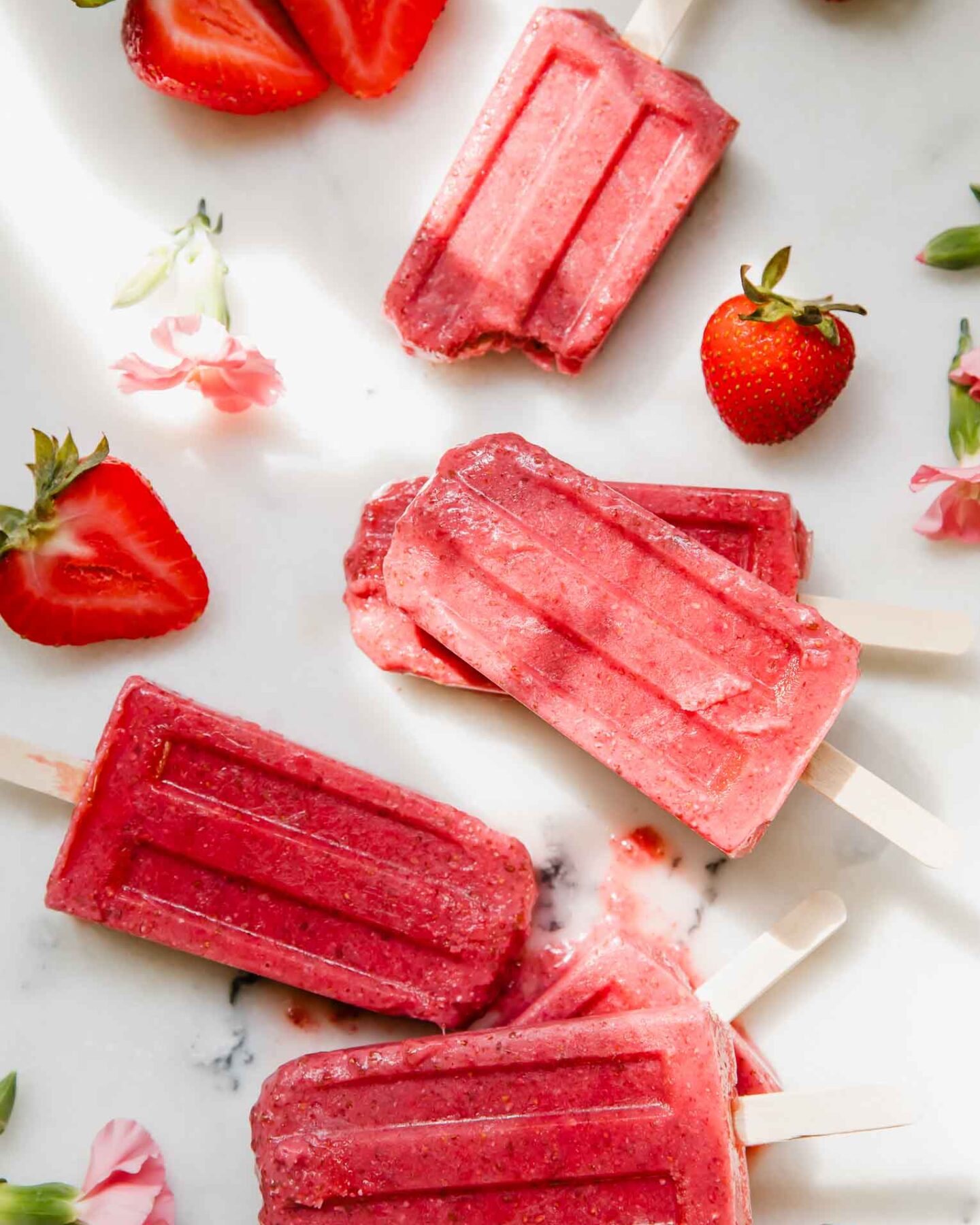 Strawberry Chia Seed Popsicles on a marble countertop.
