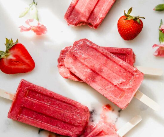 Strawberry Chia Seed Popsicles on a marble countertop.