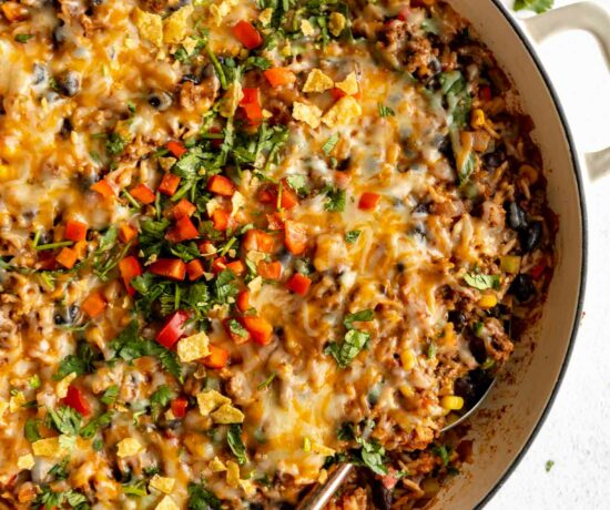 Close up top shot of Ground Beef & Rice Casserole in a skillet with a spoon.