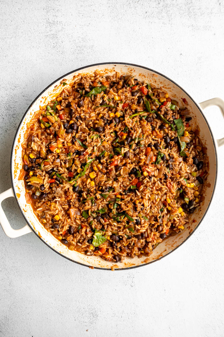 Cooked ground beef and rice in a skillet.