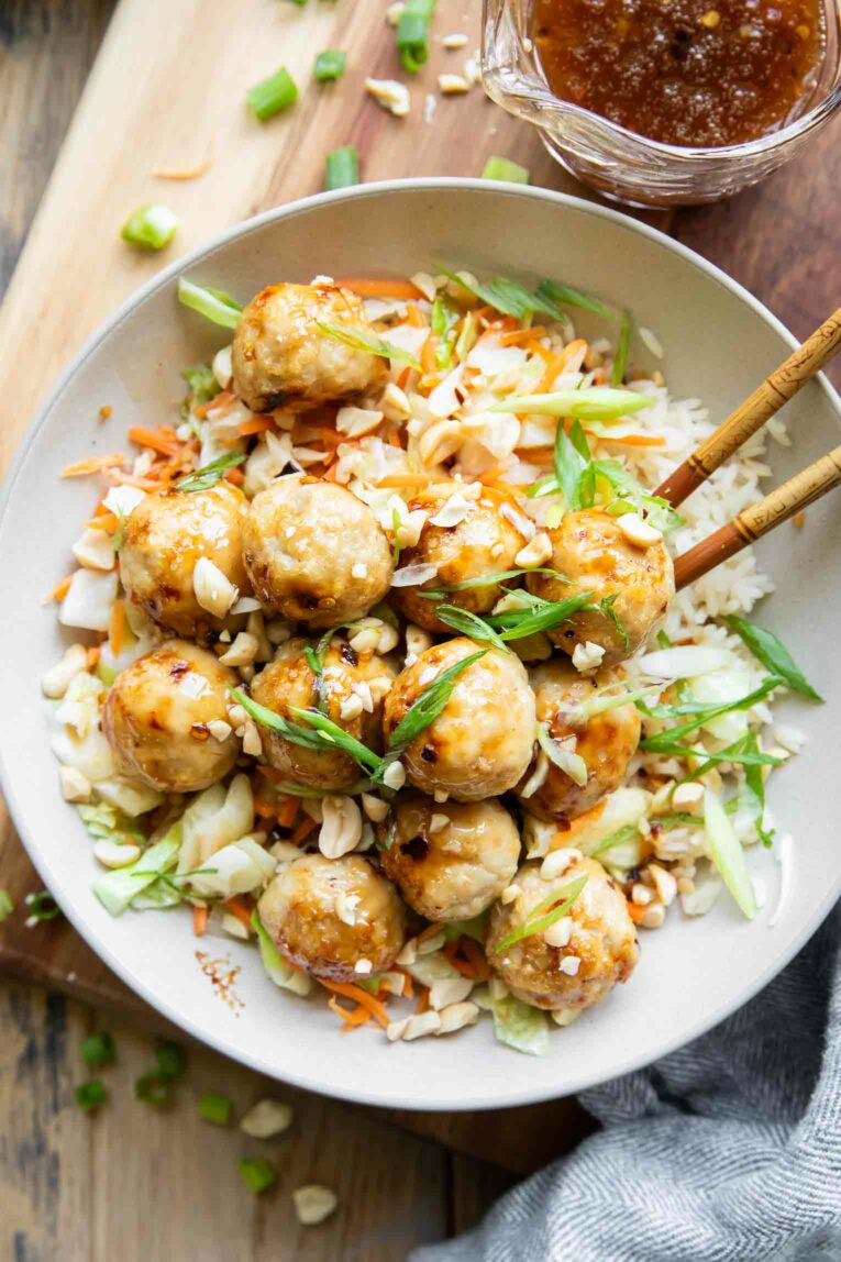 Top shot of Sweet Chili Chicken Meatballs in a bowl with rice and chopsticks.
