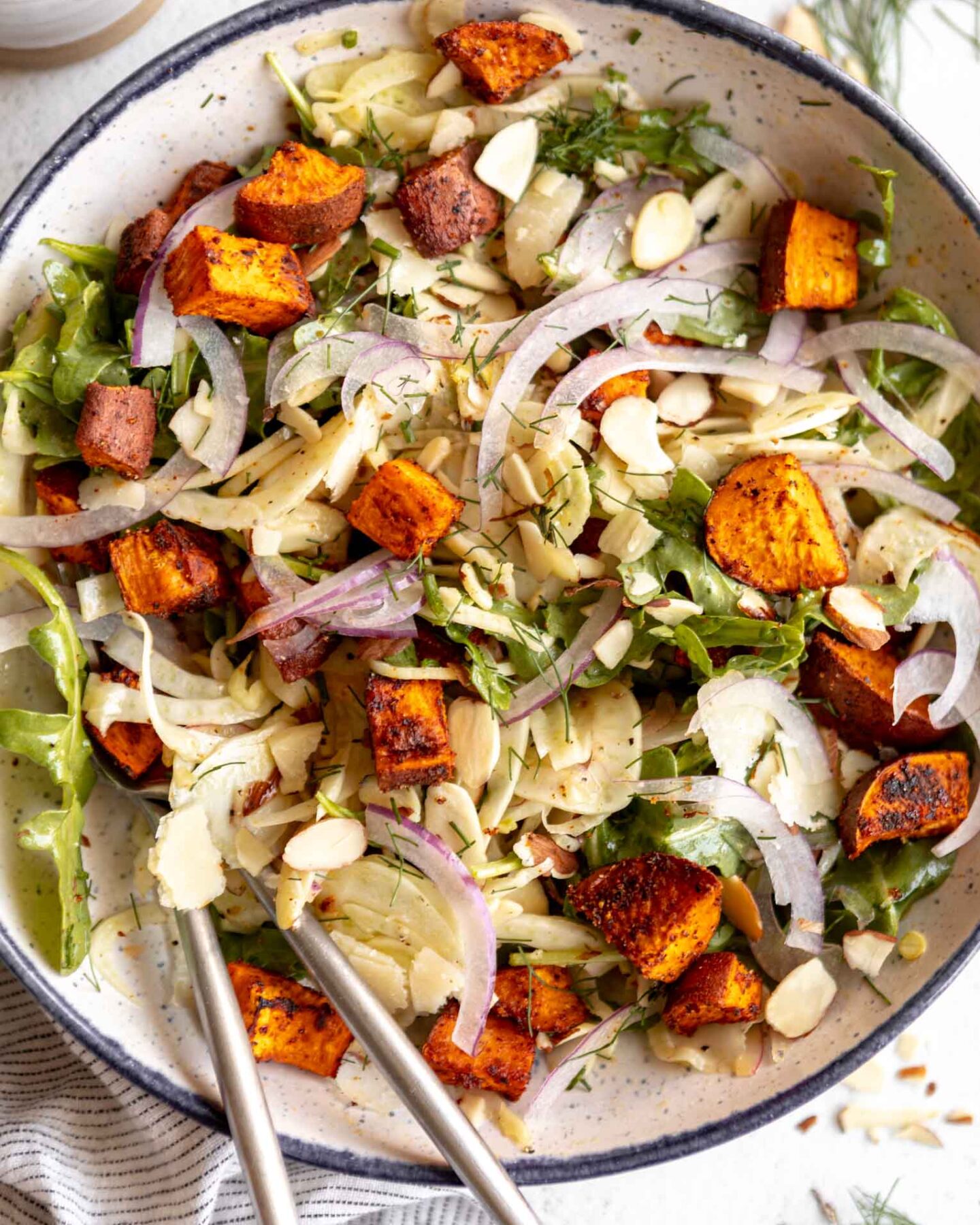 Close up of shaved fennel salad with sweet potatos on a plate.