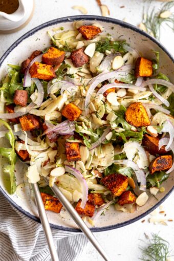 Close up of shaved fennel salad with sweet potatos on a plate.