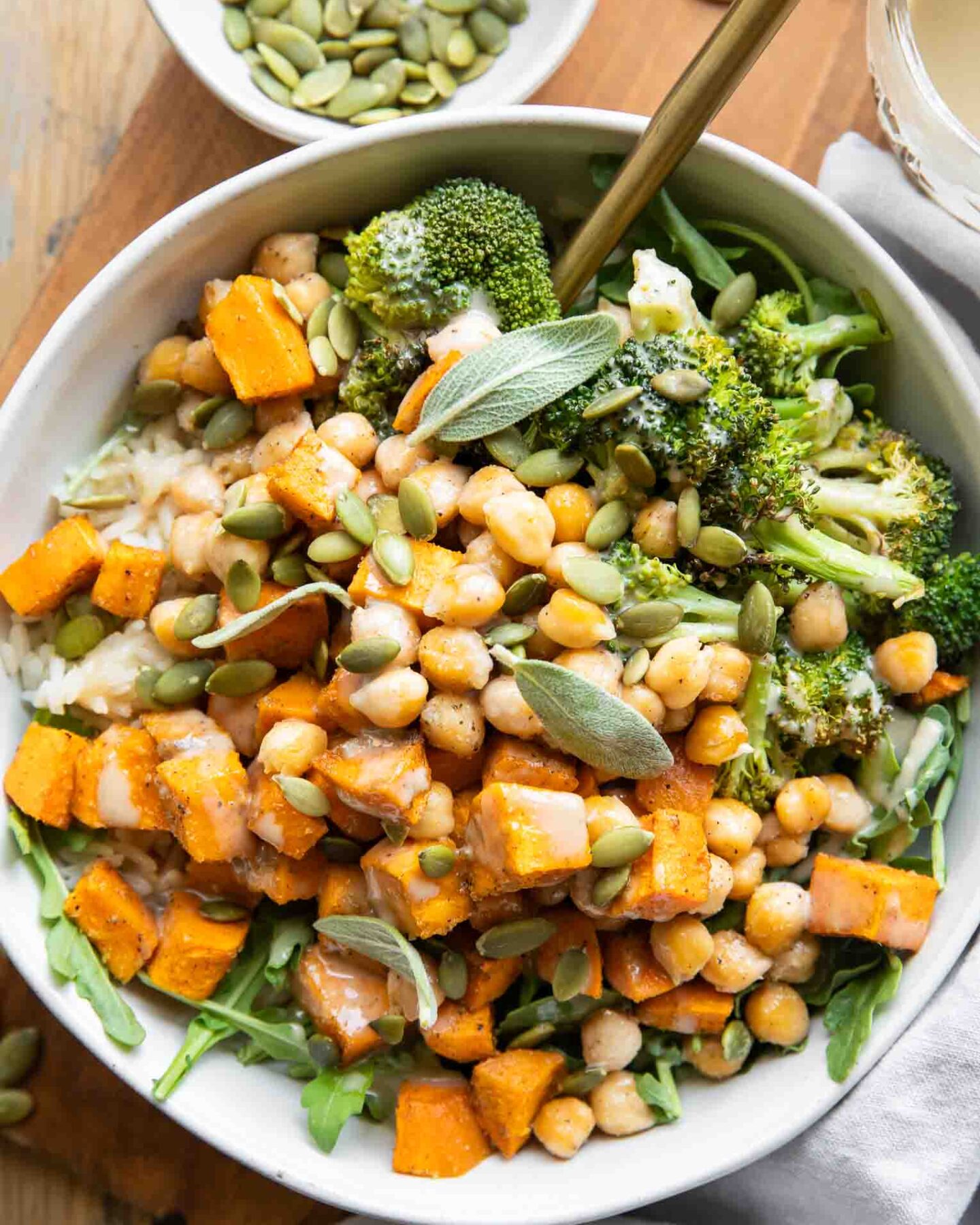 Roasted Chickpea Sweet Potatoes in a bowl with a fork and maple tahini sauce.