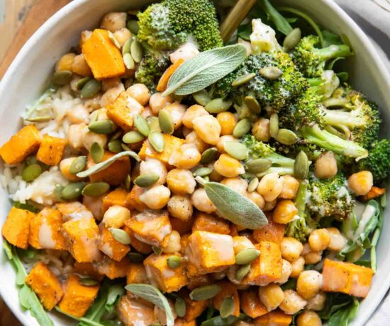 Roasted Chickpea Sweet Potatoes in a bowl with a fork and maple tahini sauce.