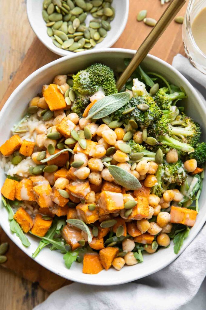 Roasted Chickpea Sweet Potatoes in a bowl with a fork and maple tahini sauce.