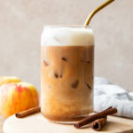 Iced Apple Crisp Cream Chai recipe in a glass with a straw.