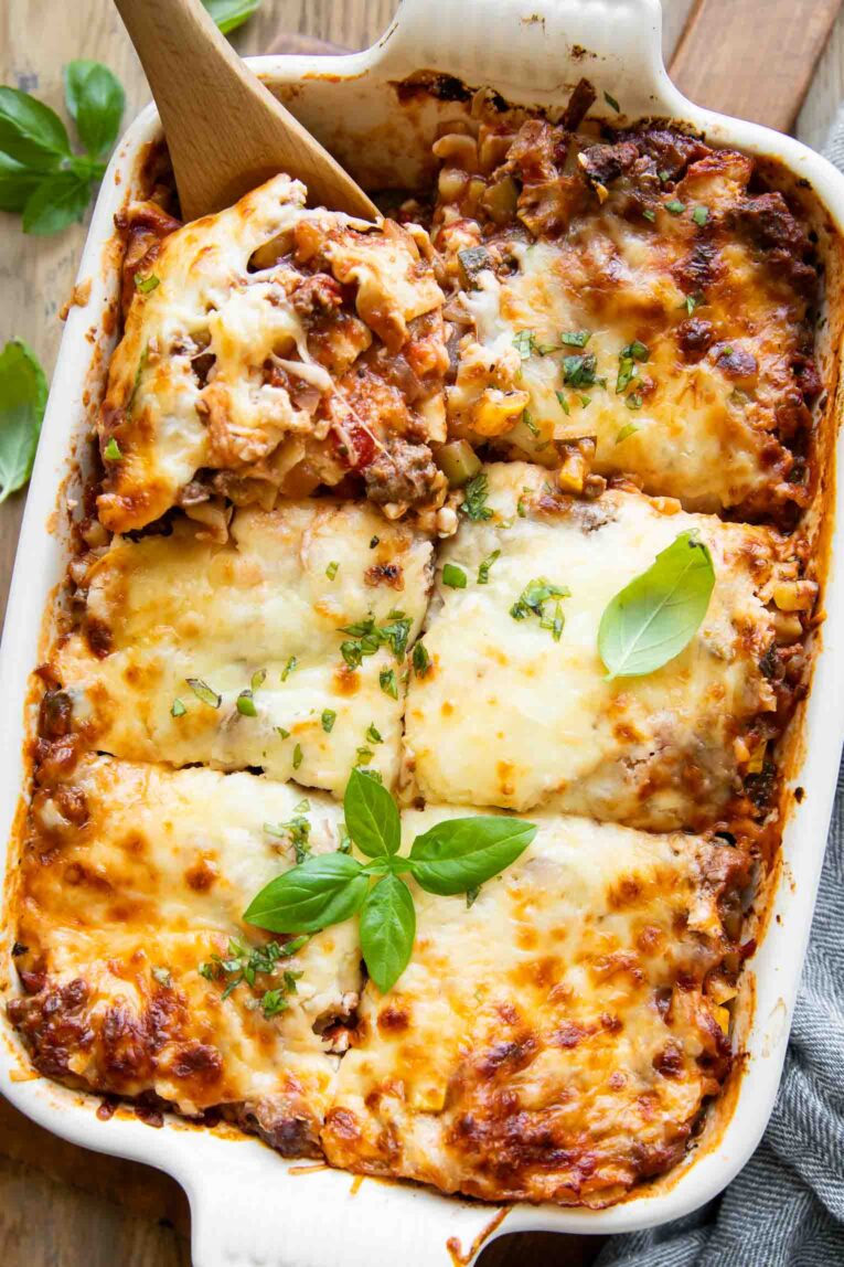 Top shot of healthy lasagna recipe with a wooden spoon taking out a slice.