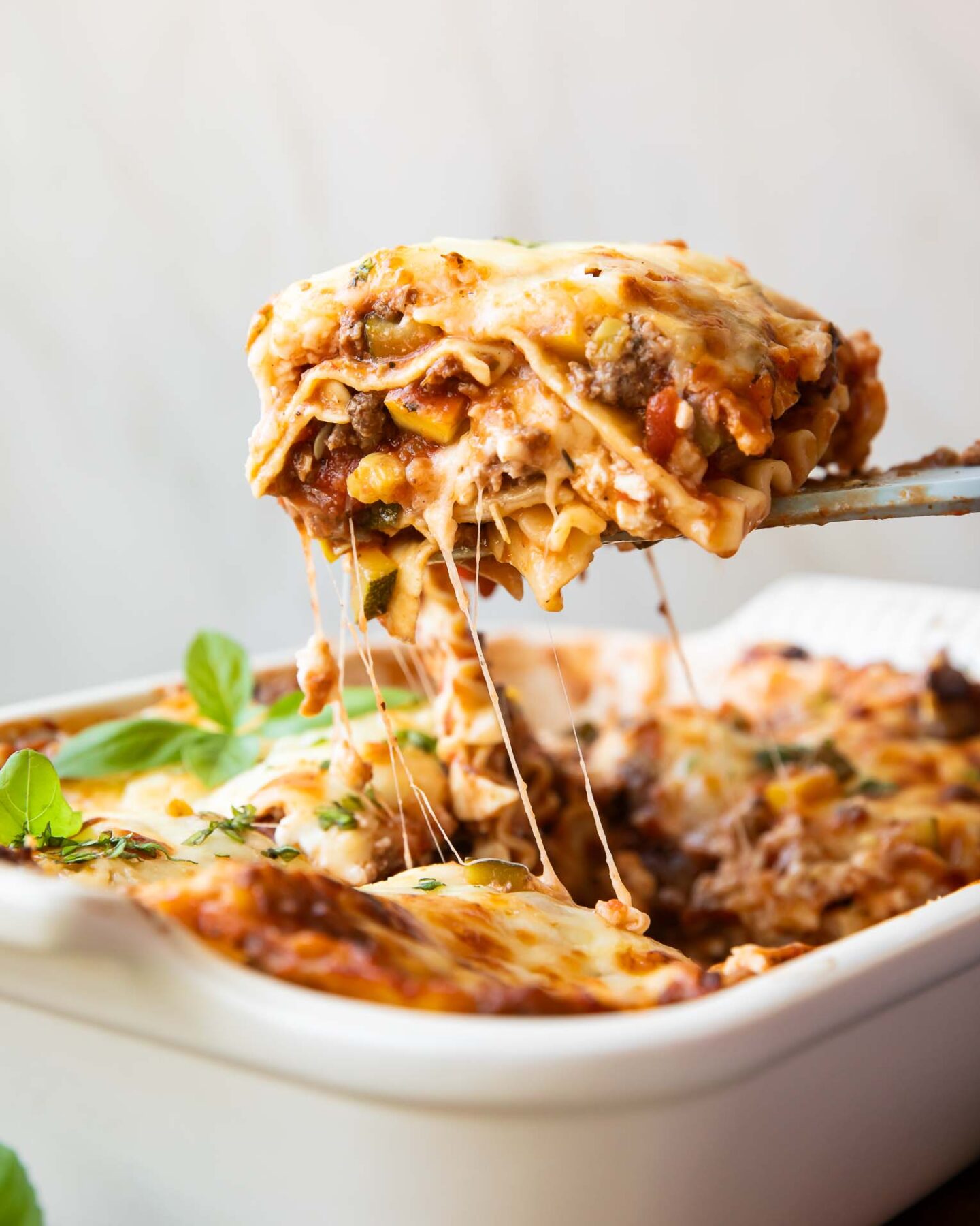 Across photo of healthy lasagna recipe slice being taken out of dish.