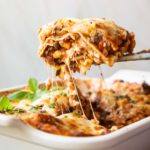 Across photo of healthy lasagna recipe slice being taken out of dish.