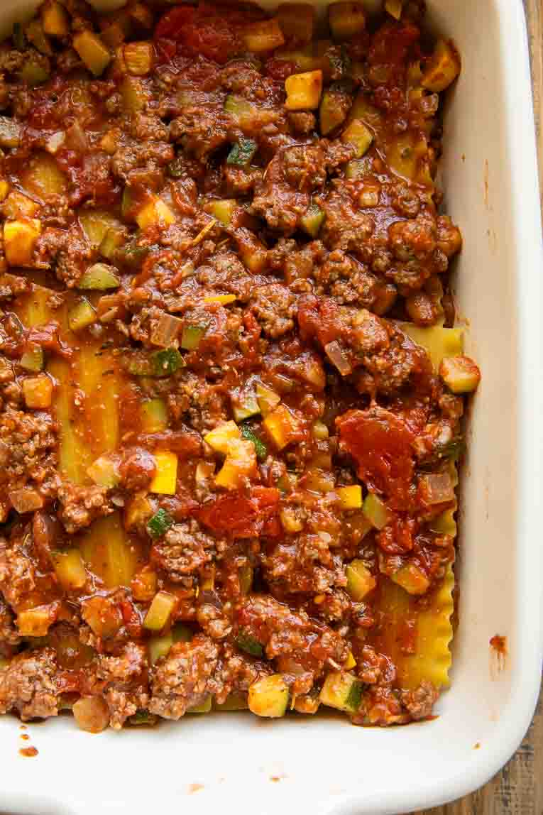 Sauce and lasagna noodles in a casserole dish.