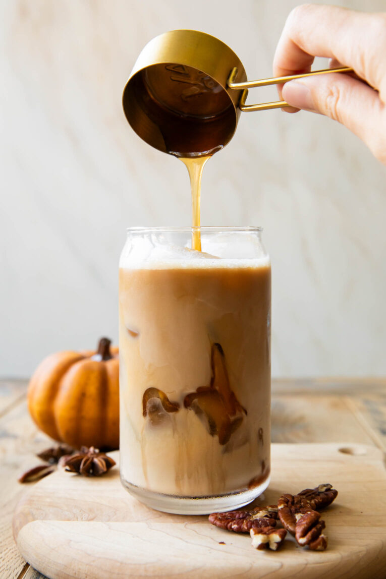 Pecan syrup being poured into an iced oat milk latte.