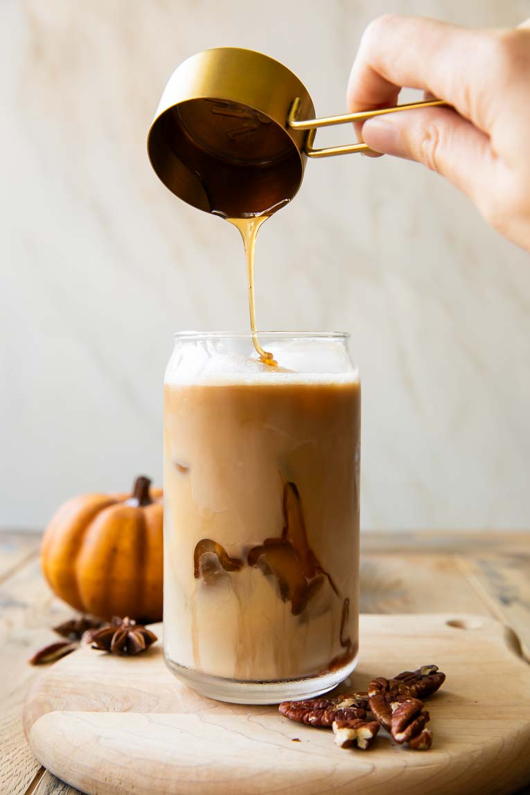 Pecan syrup being poured into an oat milk latte.