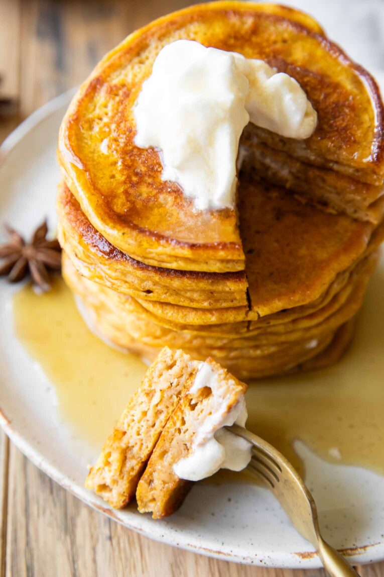 Top shot photo of Pumpkin Protein Pancakes with a bite taken out.