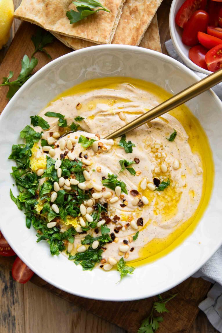 Top shot photo of Whipped Feta Dip with pine nuts, parsley, olive oil, and tomatoes.