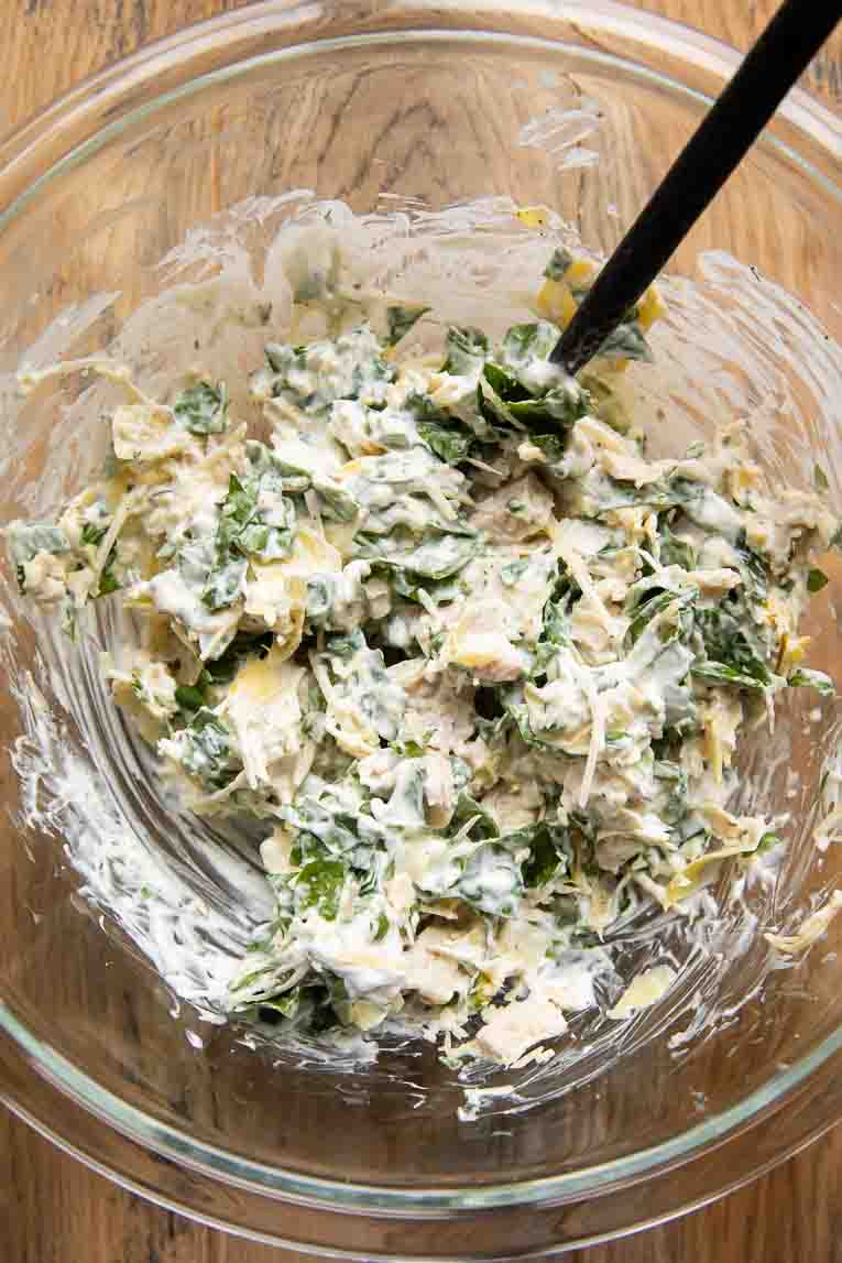 Ingredients for chicken stuffed shells filling being mixed in a bowl.