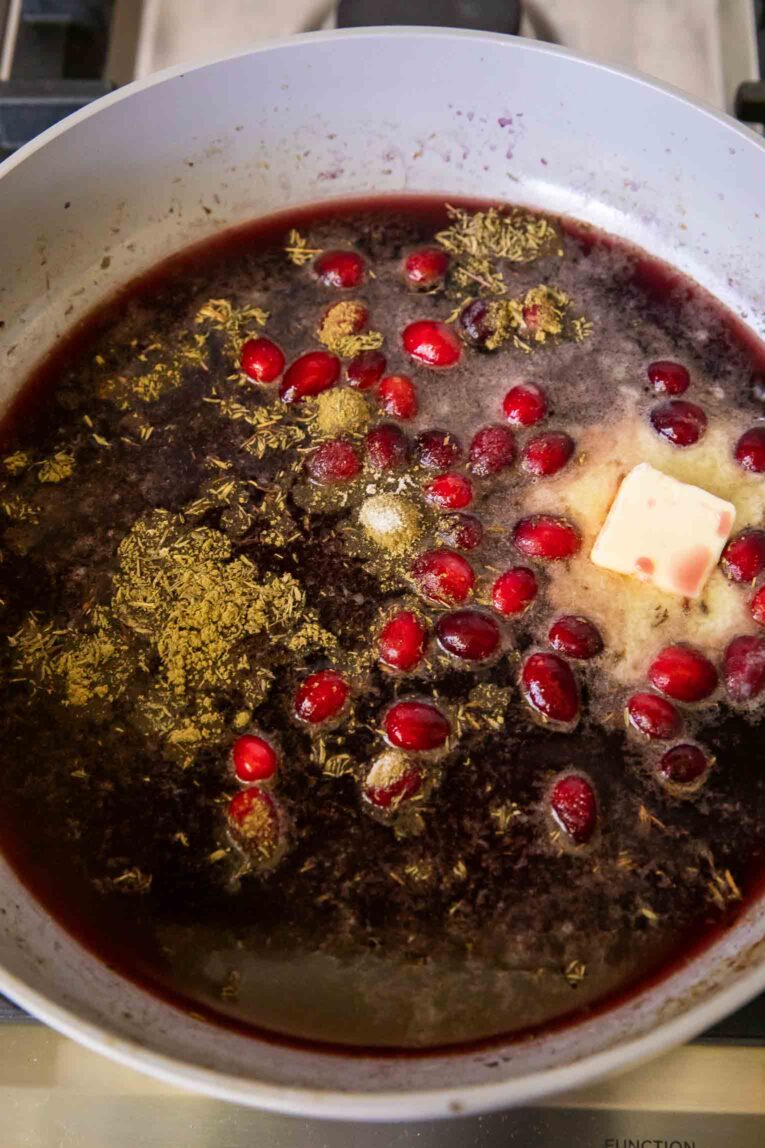 Cranberry Sauce being cooked with red wine in a pan.