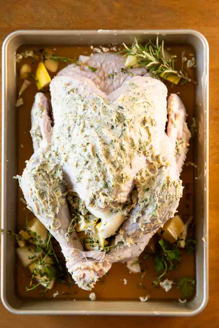 Stuffed turkey in a roasting pan with herb butter.