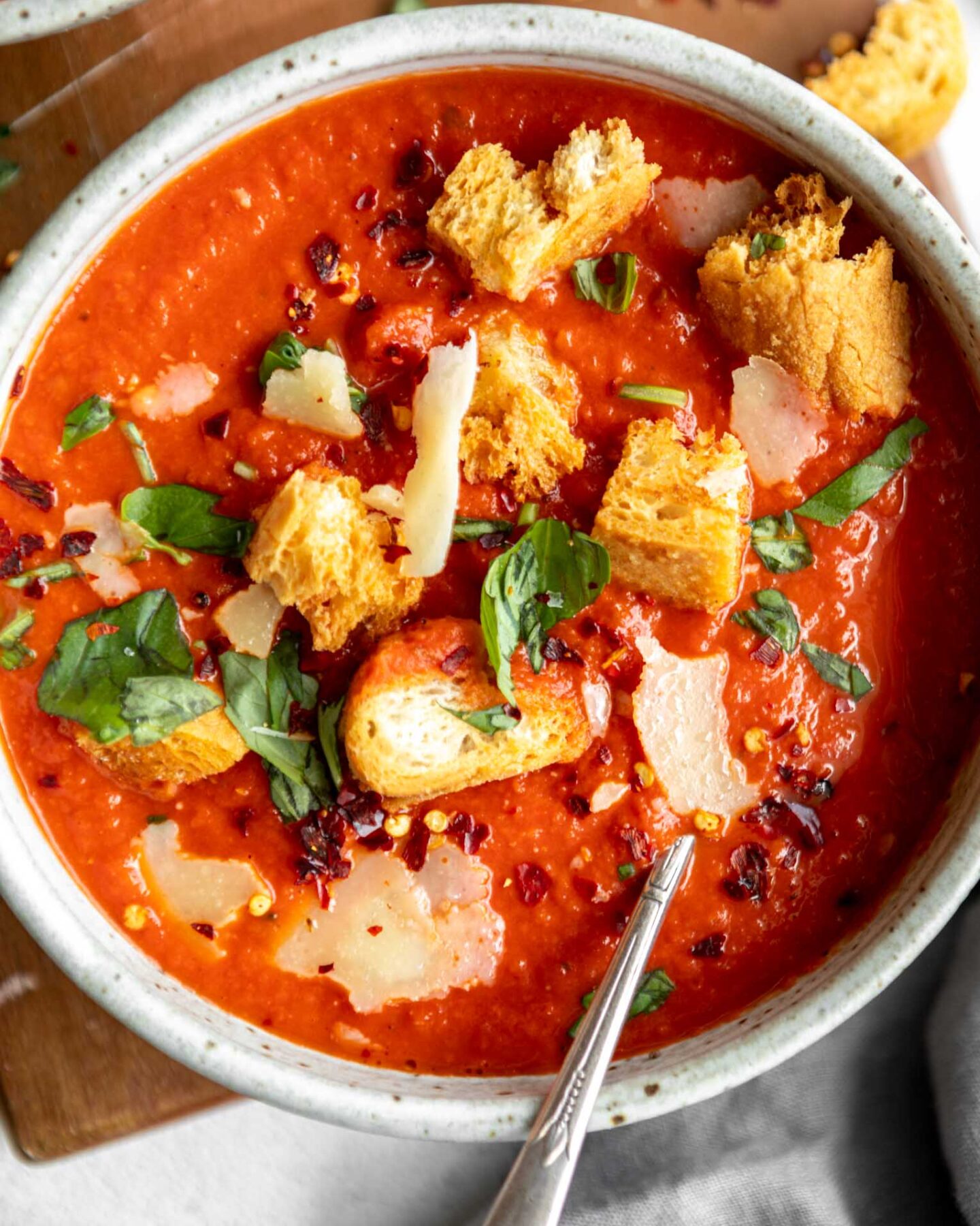 The BEST easy tomato soup recipe in a bowl with basil and croutons.