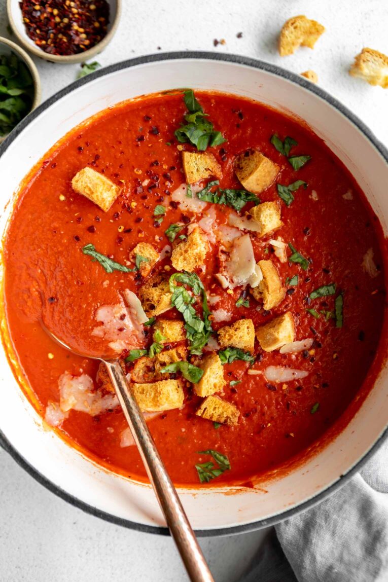 Tomato Soup recipe in a dutch oven with a large spoon.