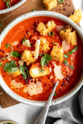 The BEST easy tomato soup recipe in a bowl with basil and croutons.