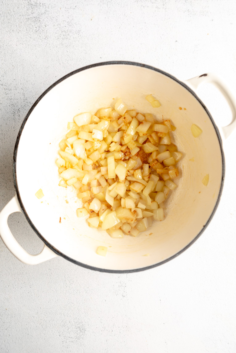 Onions cooking in oil in a dutch oven for soup.