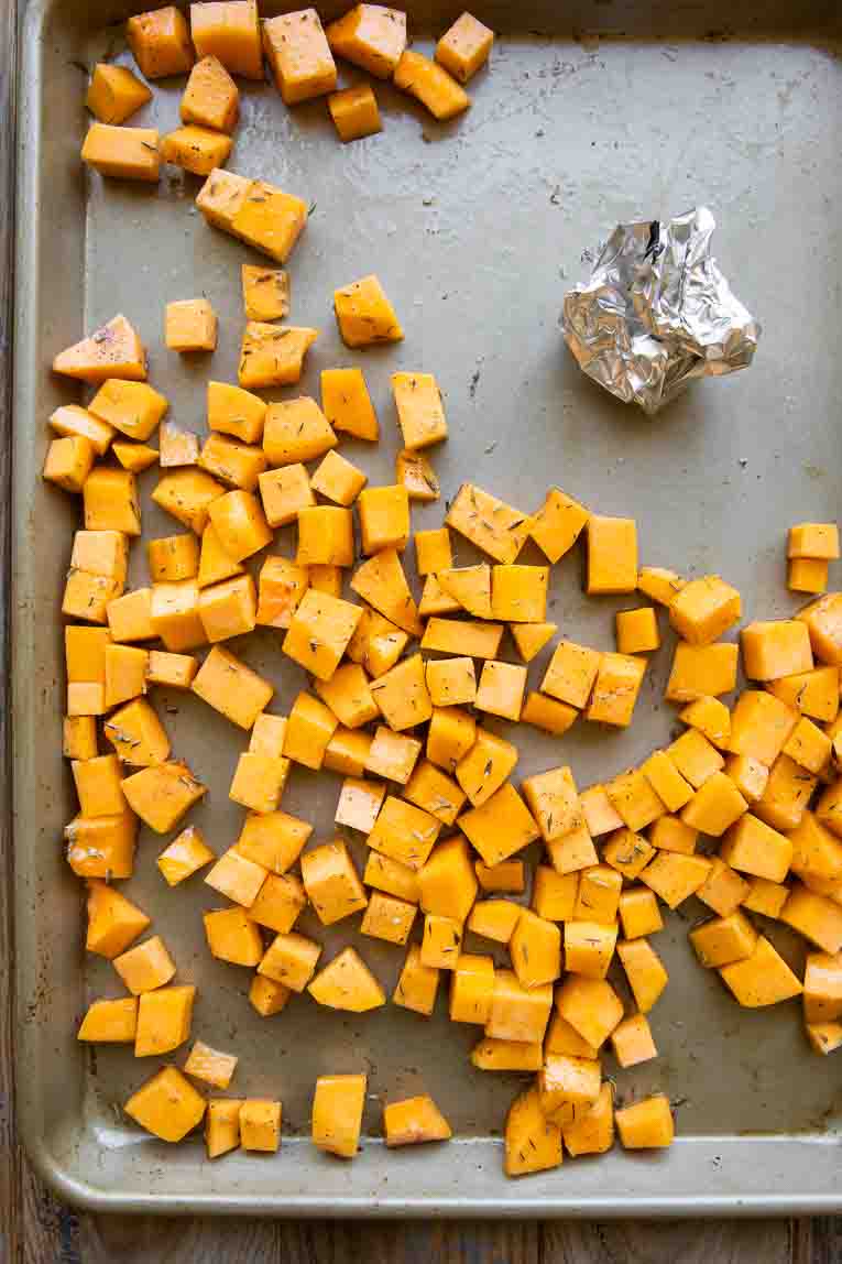 Butternut squash and garlic on a sheet pan.