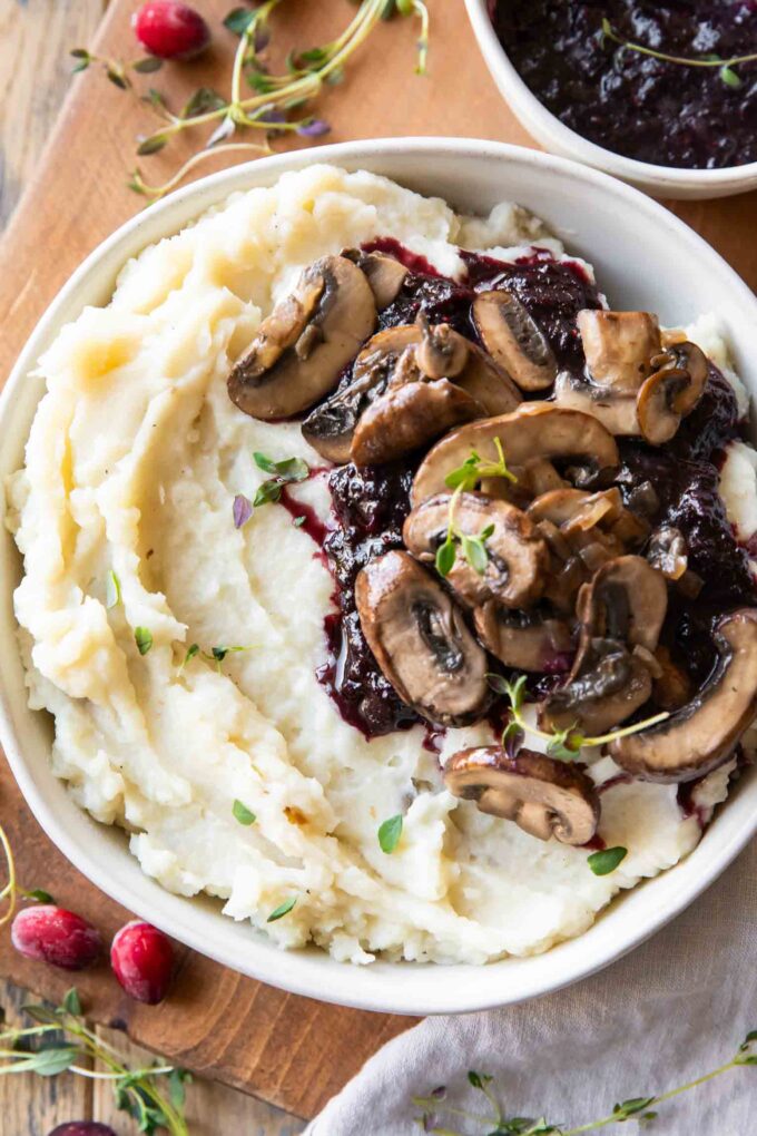Slow Cooker Mashed Potatoes in a bowl with cranberry mushroom sauce.