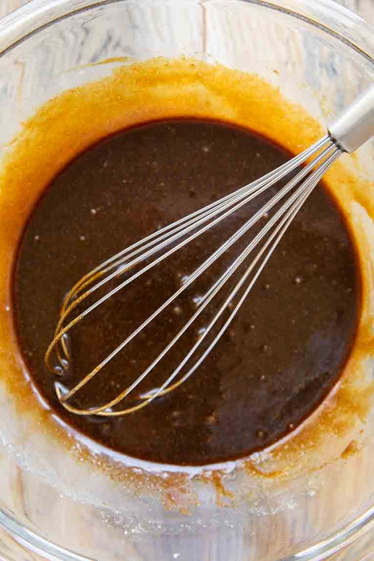 Whisked liquid ingredients for molasses cookies in a mixing bowl.