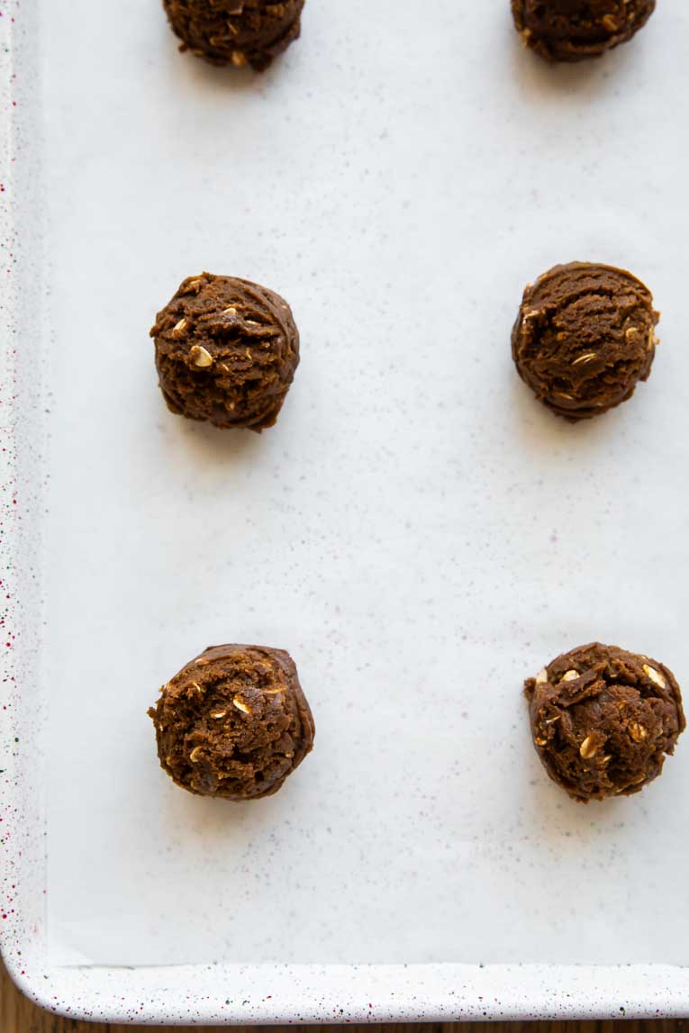 Ginger Oatmeal Molasses Cookie dough scooped on to a baking sheet.