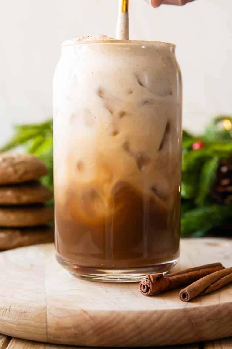 Iced Gingerbread Oatmilk Chai being stirred in a glass.