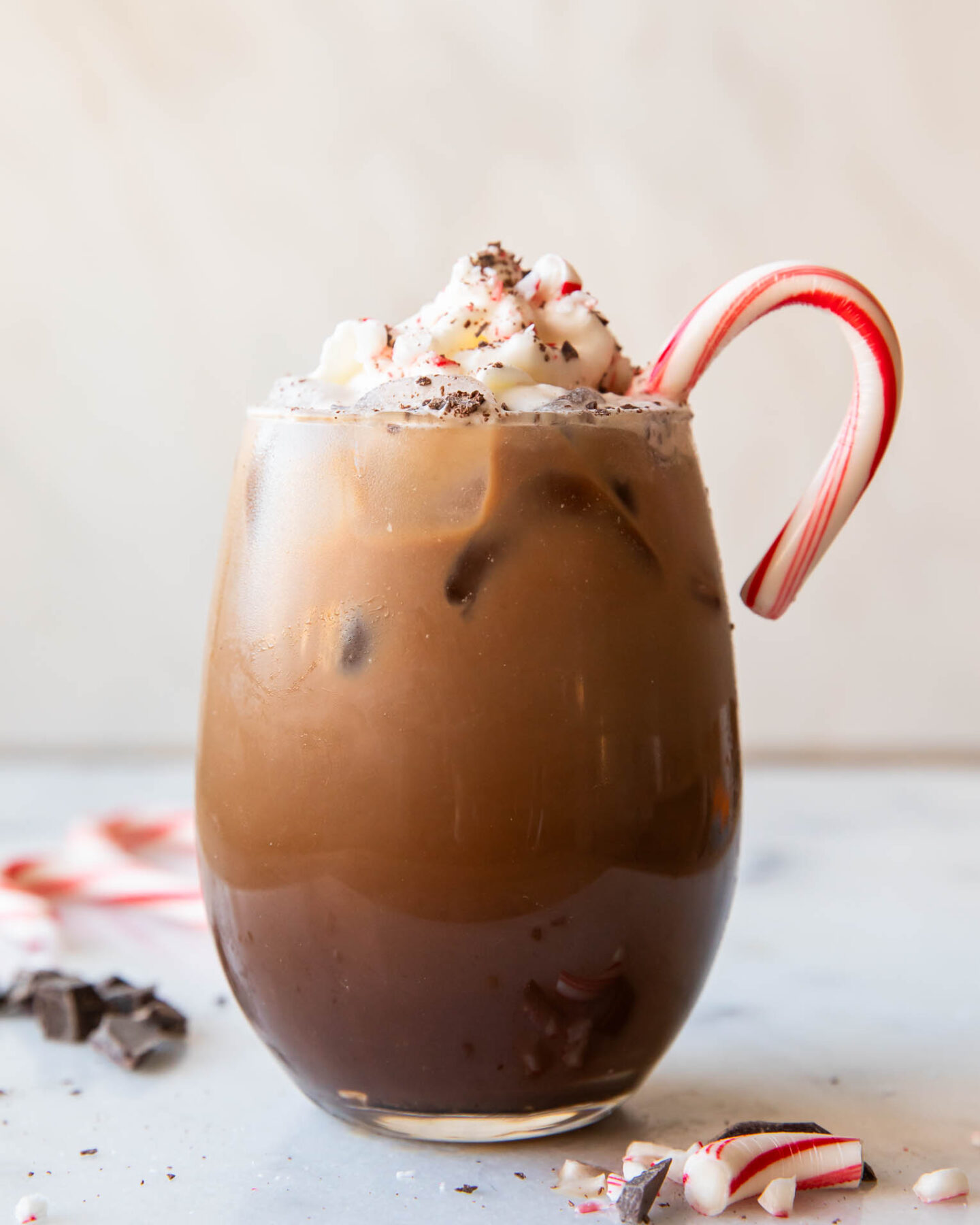 Iced Peppermint Mocha in a glass with whipped cream and candy cane.