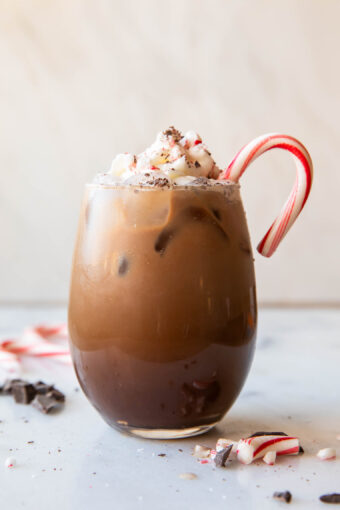 Iced Peppermint Mocha in a glass with whipped cream and candy cane.